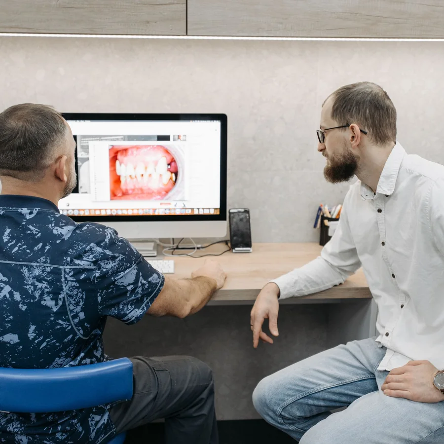Dental professionals reviewing a digital teeth model on a computer display