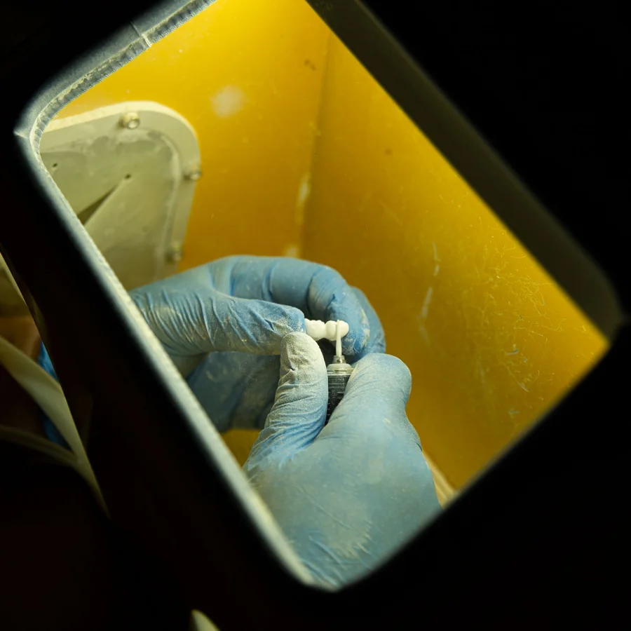 Gloved dental technician crafting a prosthetic tooth with precision tools