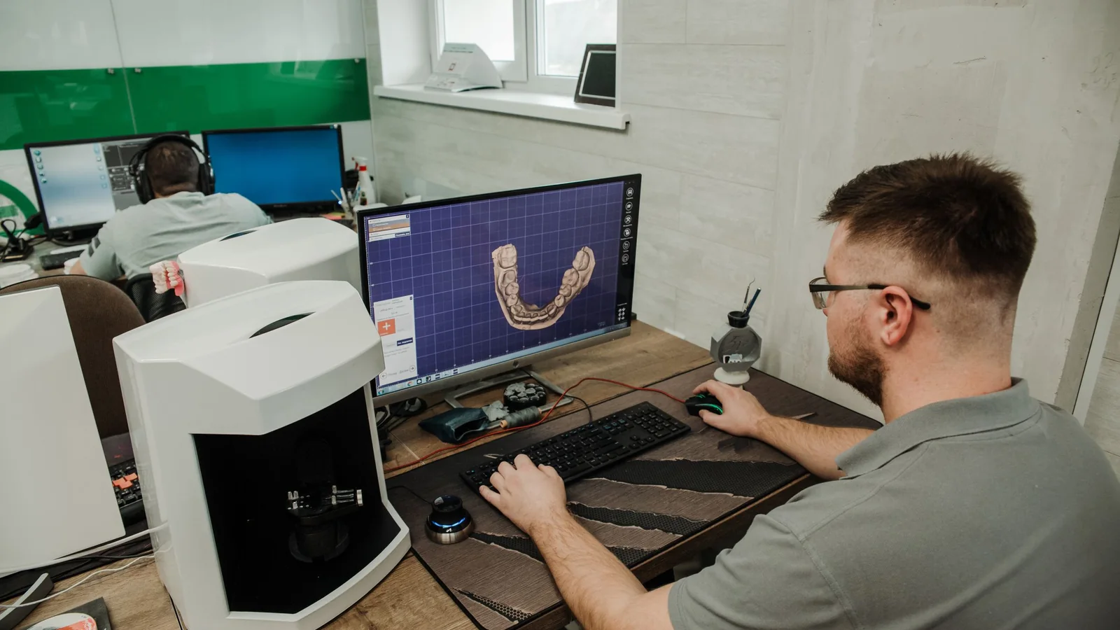 Technician designing a dental prosthetic with CAD software in a modern laboratory