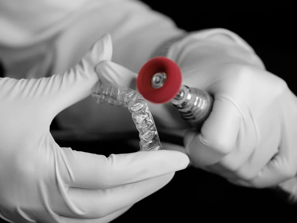 Dental technician polishing a clear orthodontic aligner in a laboratory
